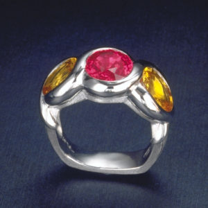 Three-stone ring wrapping platinum ribbons around a hot Pink and Yellow Sapphire suite.