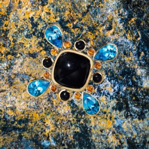 Custom made 18 karat yellow gold brooch/pendant featuring center black onyx accented by four blue topaz weighing 13.01 carats, eight citrine weighing 0.77 carats and four black onyx weighing 1.95 carats.