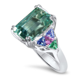 Custom-made palladium ring featuring 894 carat blue tourmaline and accented by 4-tanzanite-0.67 carats; 2-pink tourmaline=0.30 carats; 2-emerald=0.26 carats and 2-diamonds=0.10 carats.