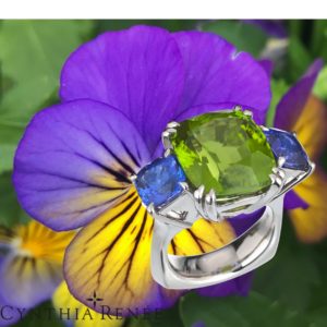 Heaven & Earth” 3-stone ring in palladium featuring stunning 16.58 carats Burmese Peridot accented by 4.75 carats pair of Tanzanite.