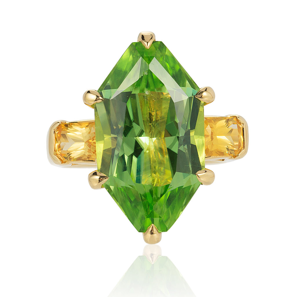 Three-stone ring in 18 kt yg featuring 10.86 ct. designer-cut Peridot accented by 1.29 ct. pair of Yellow Sapphire; size 7, but can size to fit.