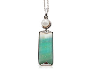 Crescent pendant in 18 karat white gold featuring 8.69 carats natural Opalized Wood and 7-7.5 mm Freshwater Pearl; the opalized wood is found in the West Java Province of Indonesia.