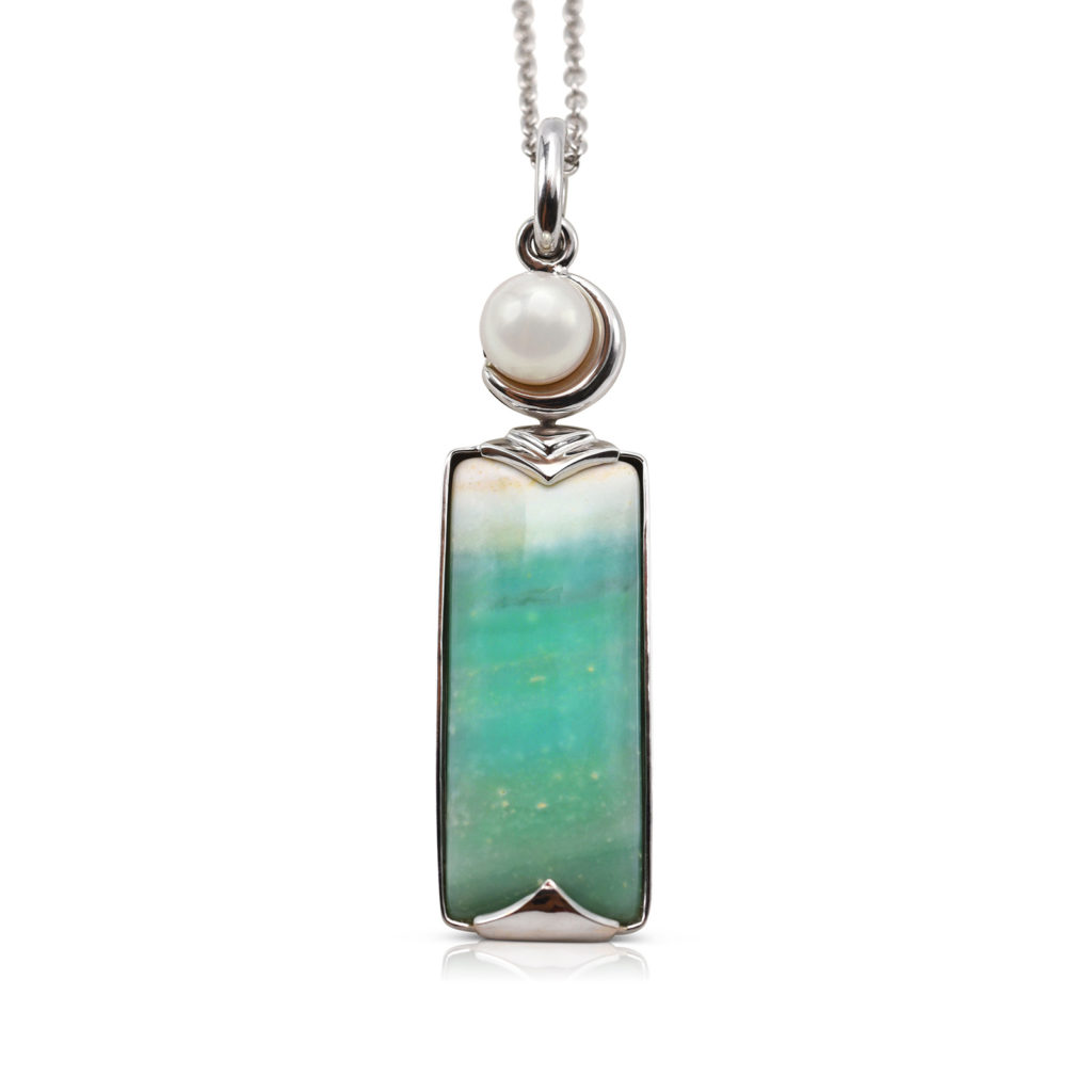 Crescent pendant in 18 karat white gold featuring 8.69 carats natural Opalized Wood and 7-7.5 mm Freshwater Pearl; the opalized wood is found in the West Java Province of Indonesia.