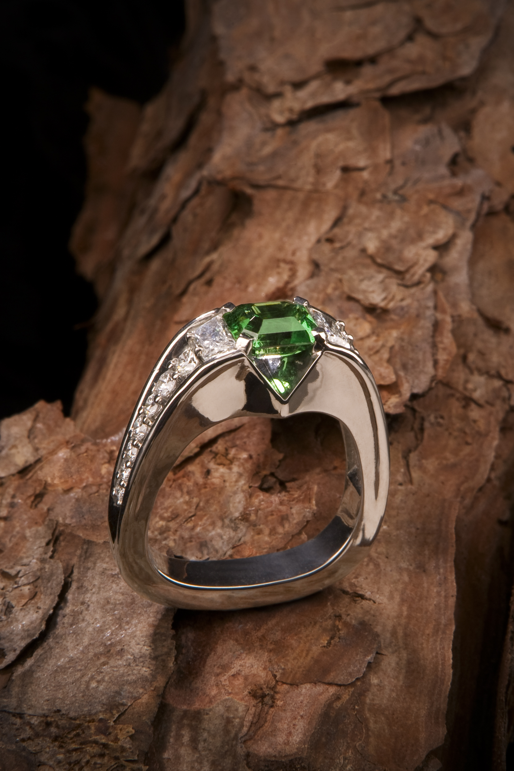 Palladium ring featuring 1.81 carat Tsavorite garnet accented by 0.55 carats of diamond trapezoids and 0.57 carats of diamond rounds.