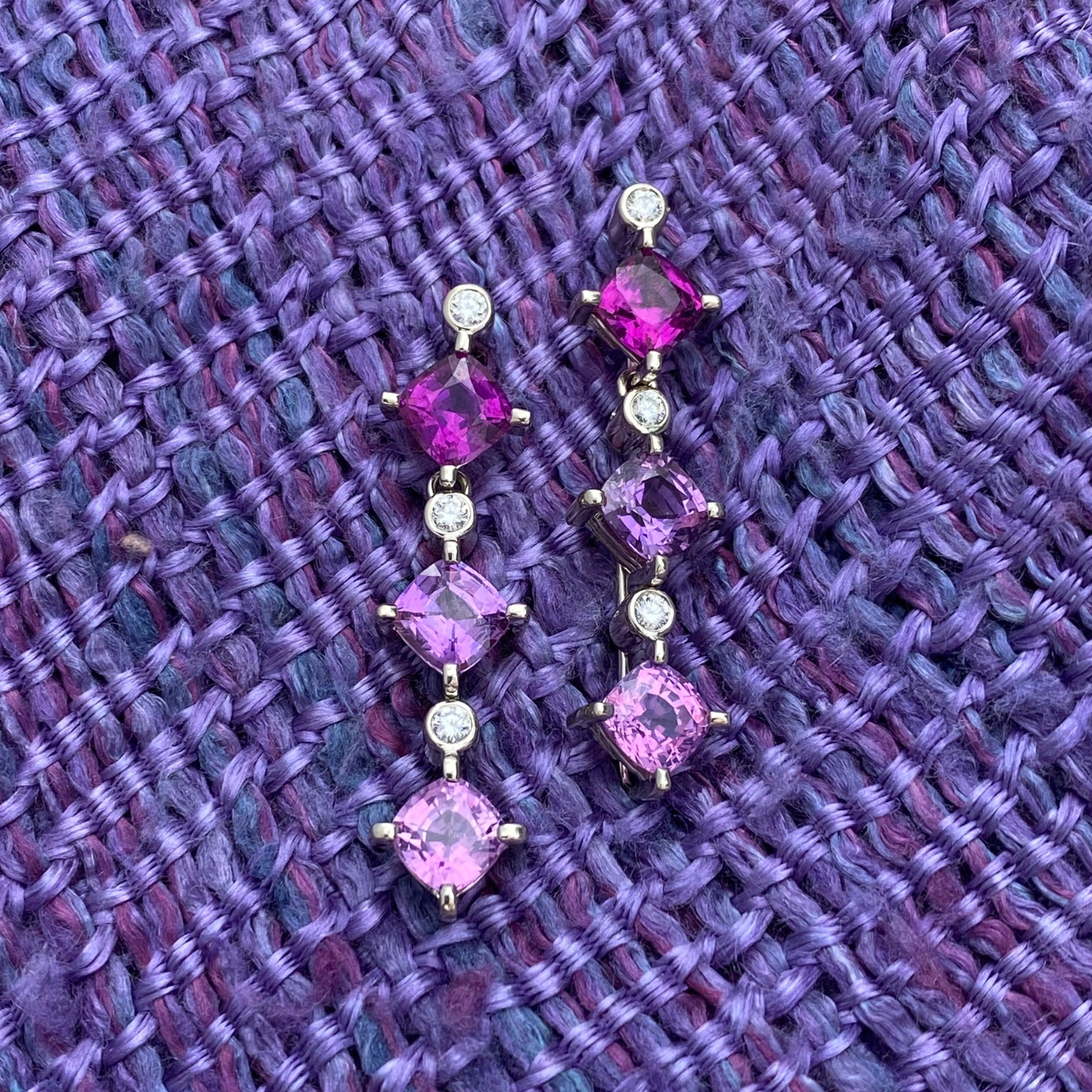 purple Mozambique garnet, purple sapphire and pink sapphire with .023 carats diamonds laid on a swatch of think-weaved purple fabric